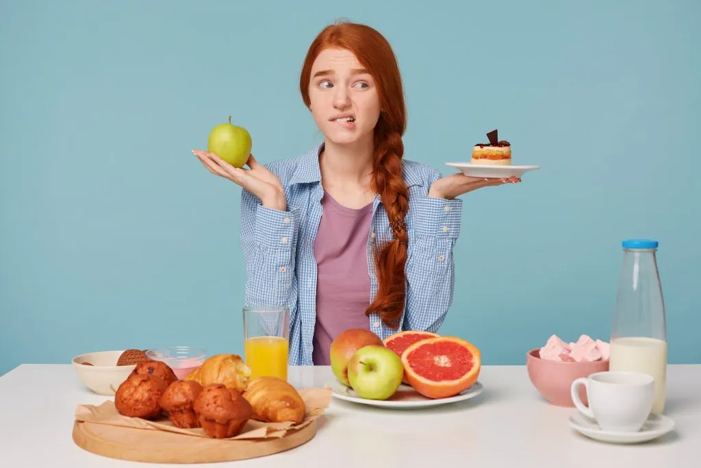 בחורה מתלבטת בין עוגה לתפוח - טיפים לירידה במשקל